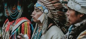 three Native Americans wearing traditional costumes